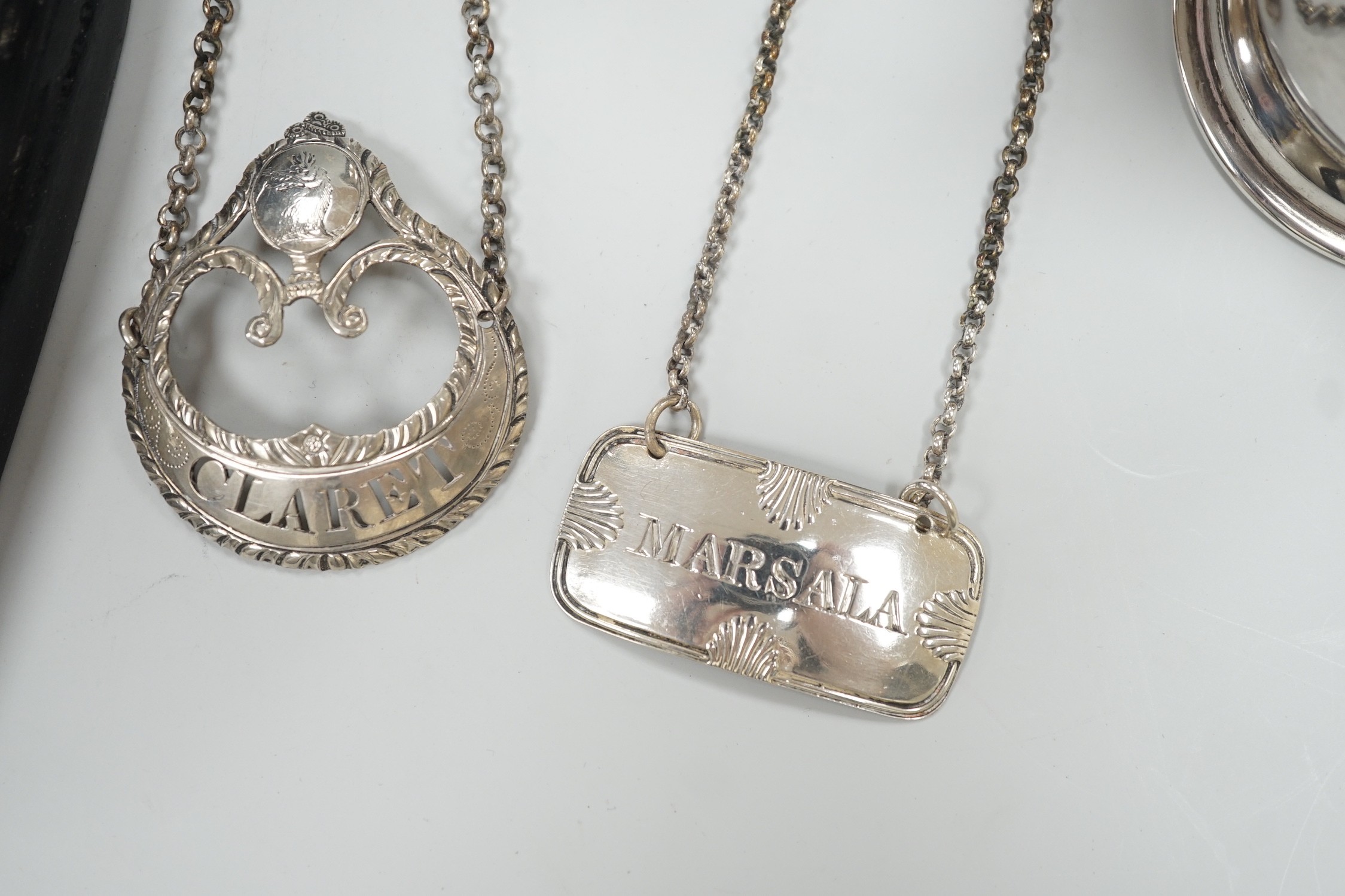 A small 1930's silver christening mug, two 19th century silver decanters labels 'Claret' and 'Marsala' and a white metal mounted polished wood shield 'Roborough School, Eastbourne Chess' and a Victorian silver oval musta